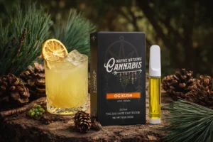 OG Kush live resin vape cartridge next to a citrus drink and pinecones