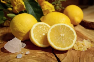 Whole and halved lemons displayed with crystals and candied lemon peel on a wooden surface